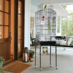 Large stainless bird cage with colorful parrots on a porch setting